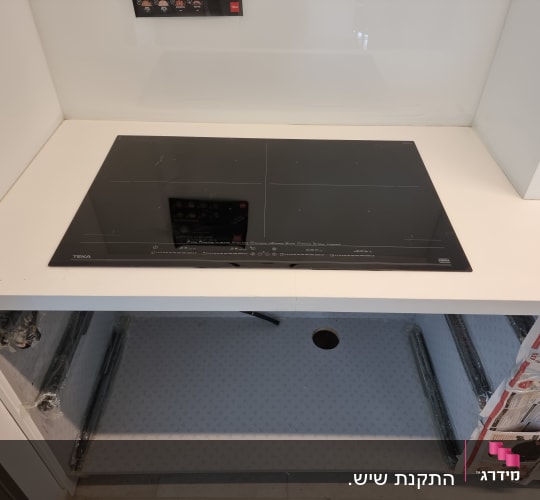 משטח שיש לבן עם כיריים שחורות מותקנות